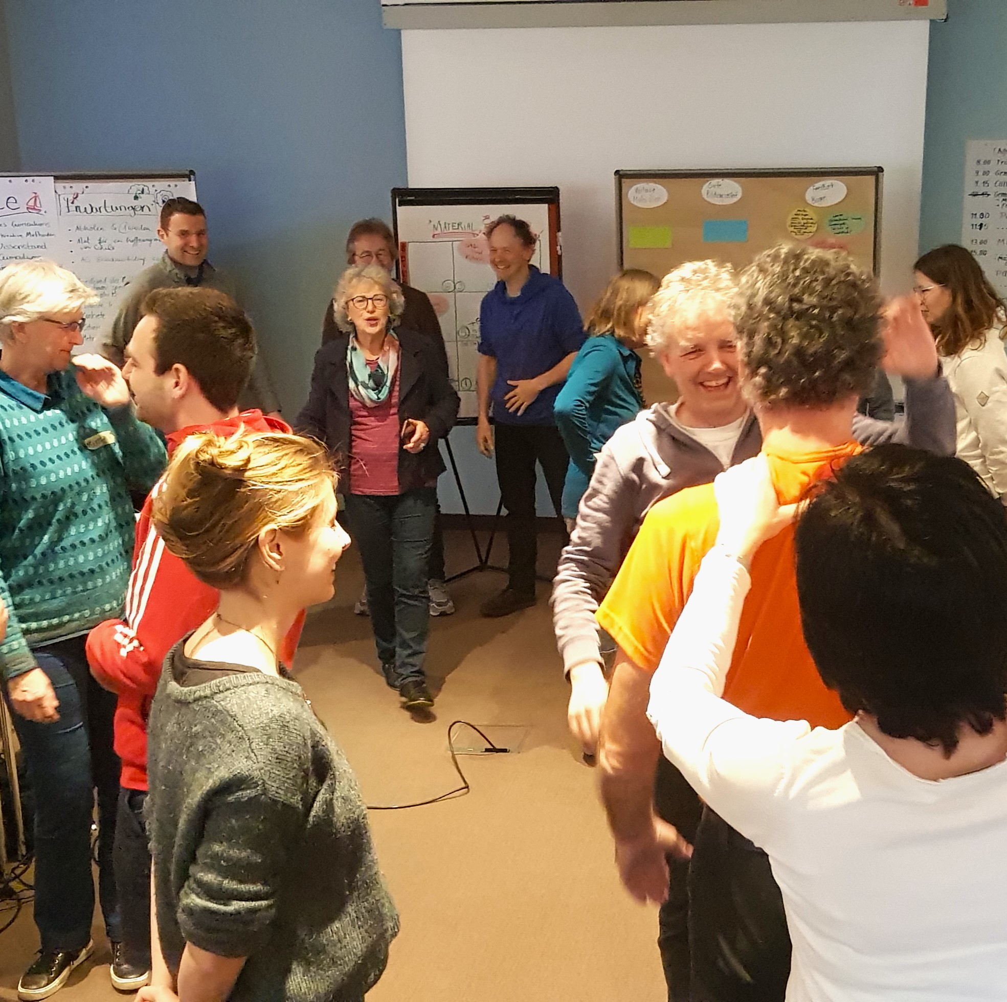 Zwölf Menschen bewegen sich im Raum während eines Workshops