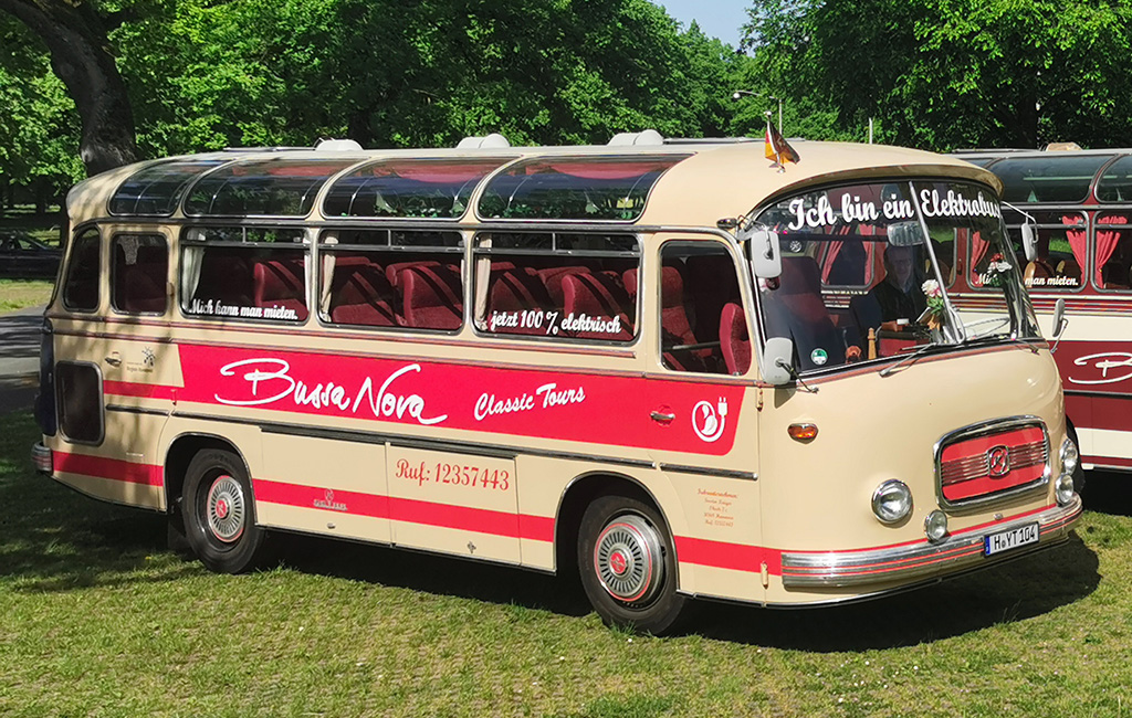 Ein Oldtimer-Bus vom Typ Setra S9 steht auf einer Wiese. Auf der Windschutzscheibe steht: Ich bin ein Elektrobus.